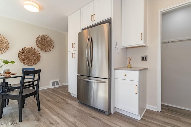 kitchen with light wood finished floors, freestanding refrigerator, and white cabinets