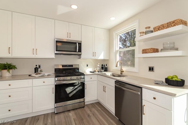 kitchen featuring a sink, white cabinetry, light wood-style floors, light countertops, and appliances with stainless steel finishes