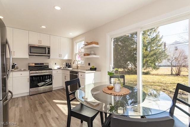 kitchen with recessed lighting, stainless steel appliances, wood finished floors, a sink, and white cabinets