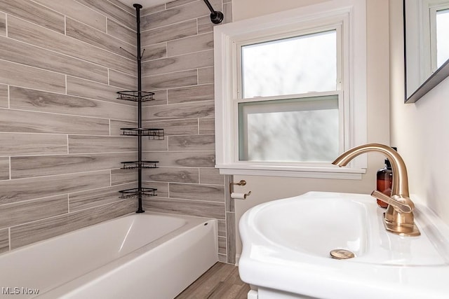 bathroom featuring tub / shower combination, a sink, and wood finished floors