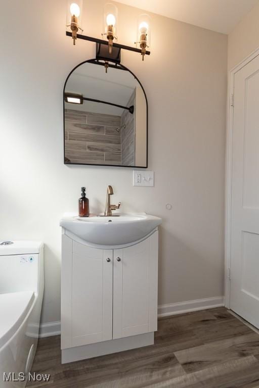 bathroom with wood finished floors, vanity, and baseboards