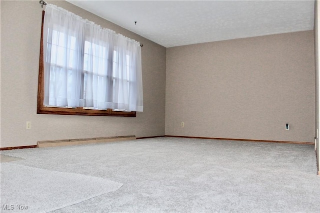 carpeted spare room with a baseboard heating unit and baseboards