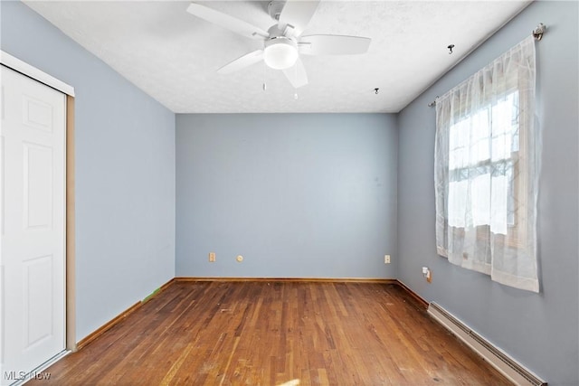 unfurnished room with a baseboard radiator, baseboards, ceiling fan, and wood finished floors