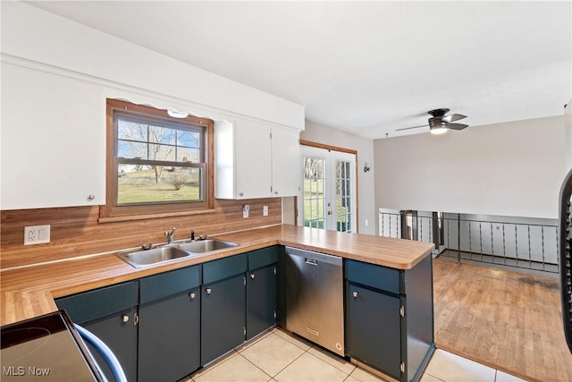 kitchen with a peninsula, a sink, light countertops, french doors, and stainless steel dishwasher