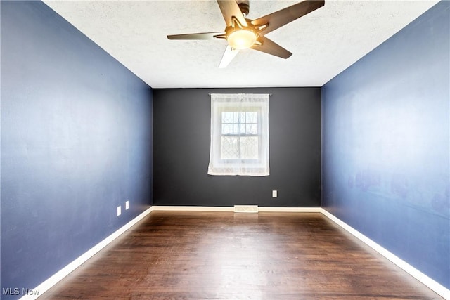 spare room with a textured ceiling, wood finished floors, and baseboards