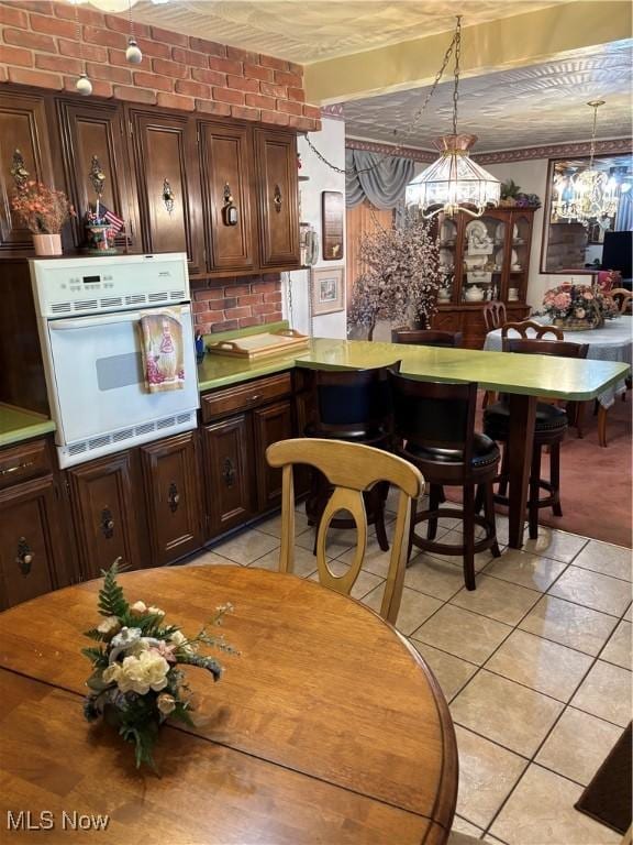 kitchen featuring an inviting chandelier, light tile patterned floors, decorative backsplash, and oven