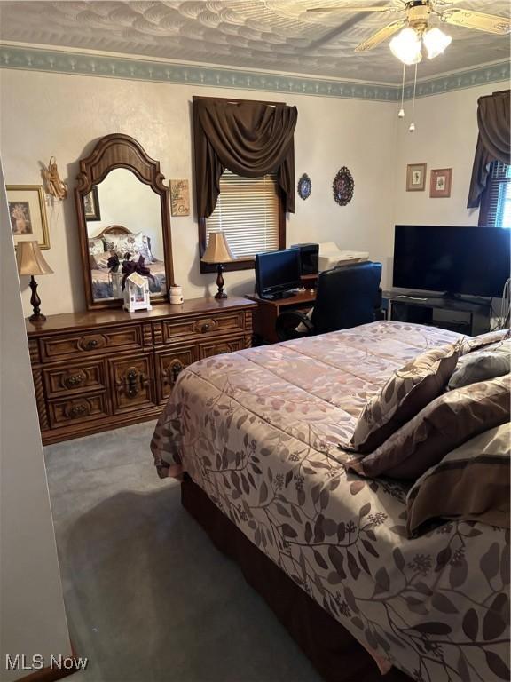 bedroom featuring ornamental molding, carpet flooring, and a ceiling fan