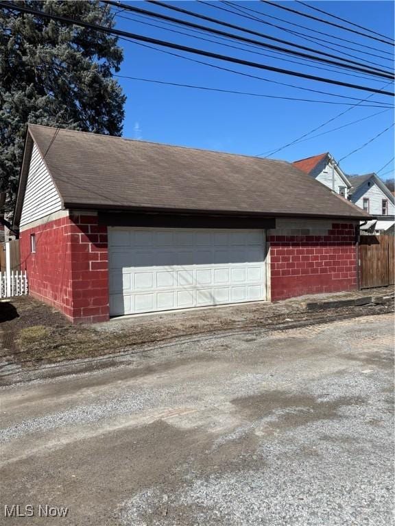 garage featuring driveway and fence