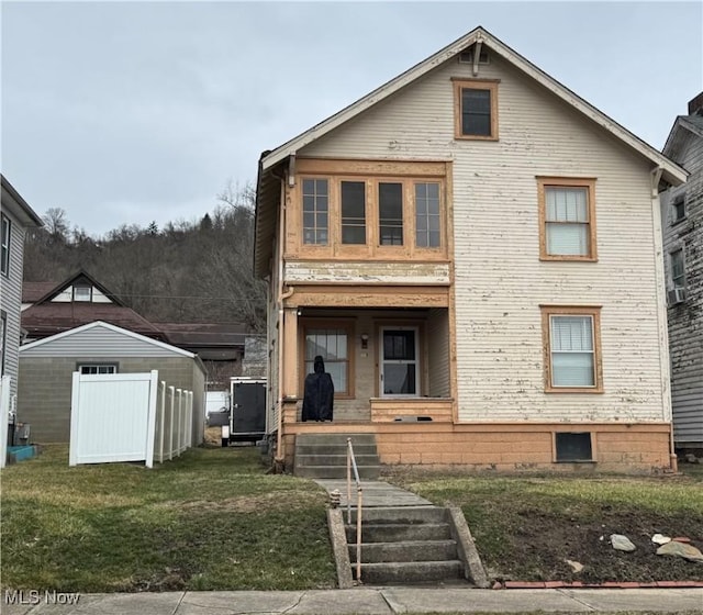 view of front facade with covered porch, fence, and a front lawn