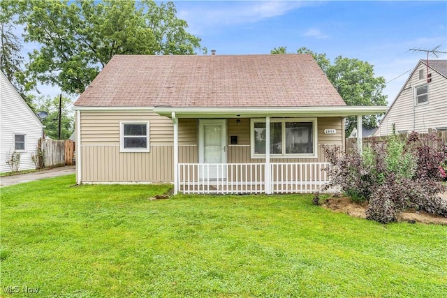 view of front of property with a shingled roof, fence, a front lawn, and a porch