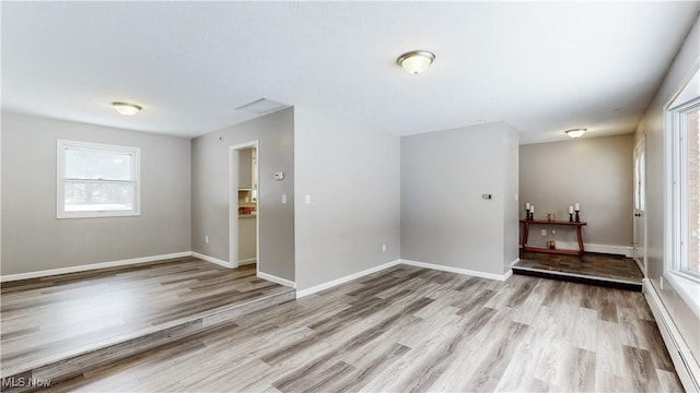 foyer entrance featuring a baseboard heating unit, visible vents, baseboards, and wood finished floors