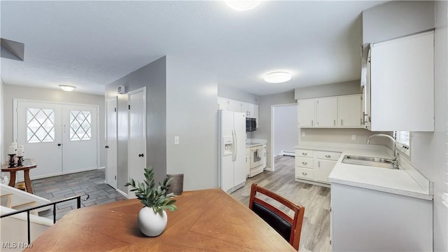 dining space with light wood-style floors, french doors, and baseboard heating