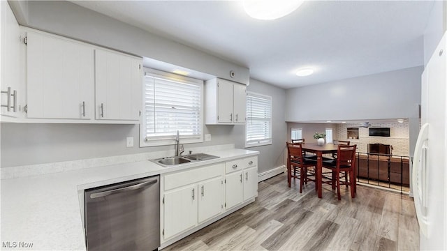 kitchen featuring dishwasher, a baseboard radiator, light wood-style flooring, light countertops, and a sink