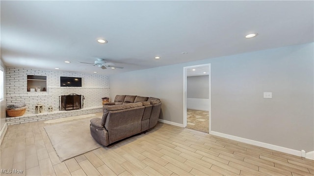 living room with recessed lighting, light wood-style flooring, a brick fireplace, ceiling fan, and baseboards