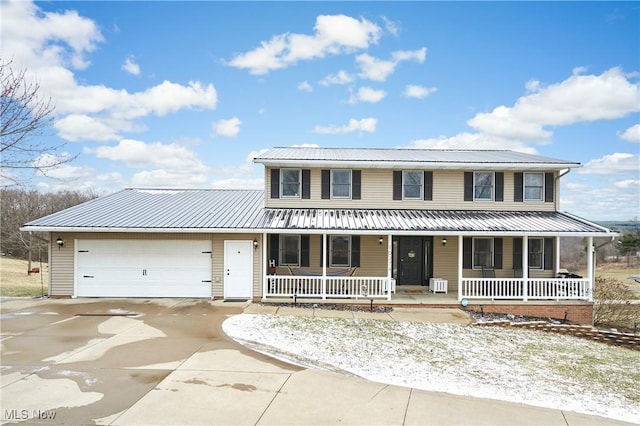 view of front facade featuring driveway, metal roof, an attached garage, and a porch