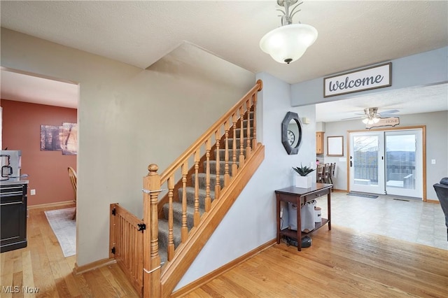 stairs featuring a textured ceiling, wood finished floors, and baseboards