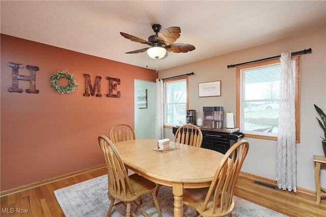 dining space featuring a ceiling fan, light wood-style flooring, and baseboards