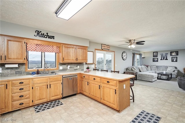 kitchen featuring a sink, light floors, light countertops, and dishwasher