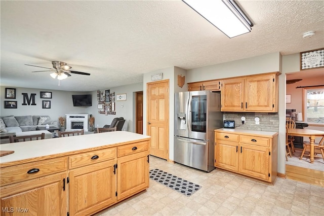 kitchen featuring a ceiling fan, light countertops, decorative backsplash, light floors, and stainless steel fridge