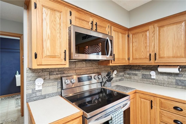 kitchen with appliances with stainless steel finishes, light countertops, and backsplash