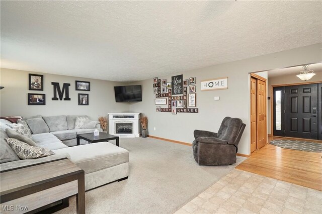 living area with a fireplace, a textured ceiling, baseboards, and tile patterned floors