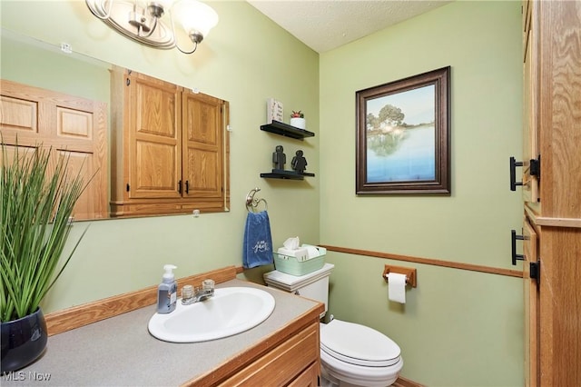 bathroom featuring a textured ceiling, vanity, and toilet