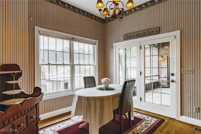 dining area featuring baseboards, wood finished floors, a wealth of natural light, and a notable chandelier