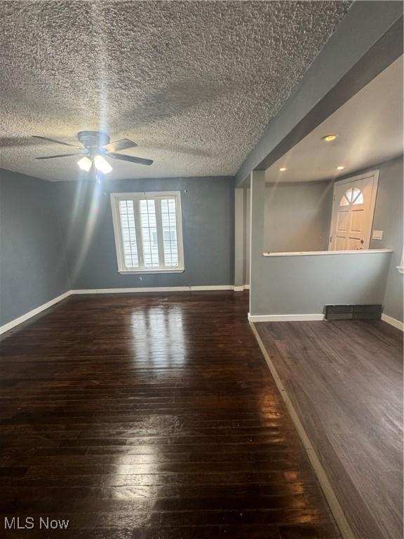 empty room with baseboards, ceiling fan, a textured ceiling, and hardwood / wood-style floors