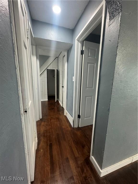 hall with baseboards and wood finished floors