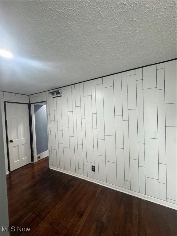 unfurnished room with a textured ceiling and dark wood-type flooring