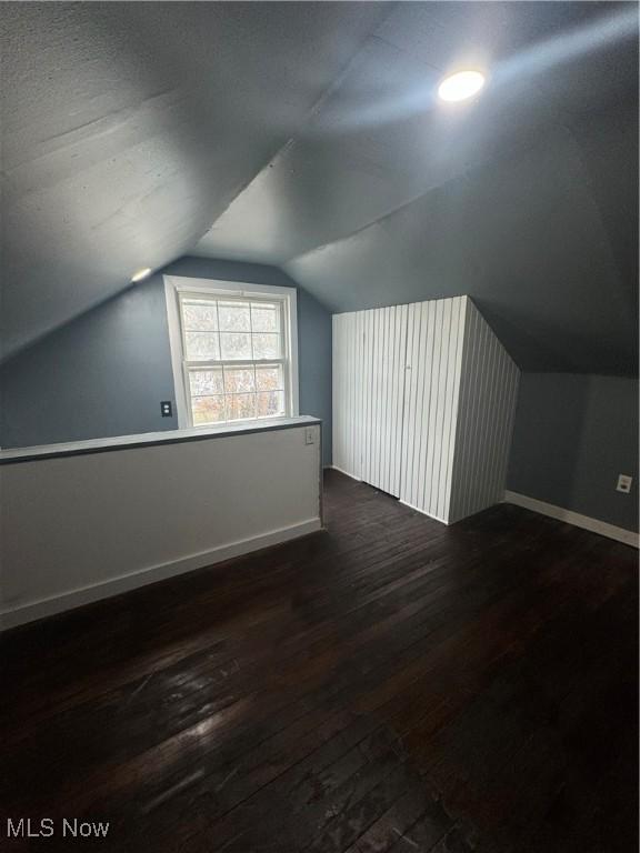 bonus room with vaulted ceiling, baseboards, and dark wood finished floors