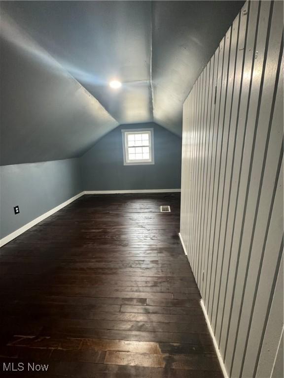 bonus room featuring lofted ceiling, hardwood / wood-style flooring, visible vents, and baseboards