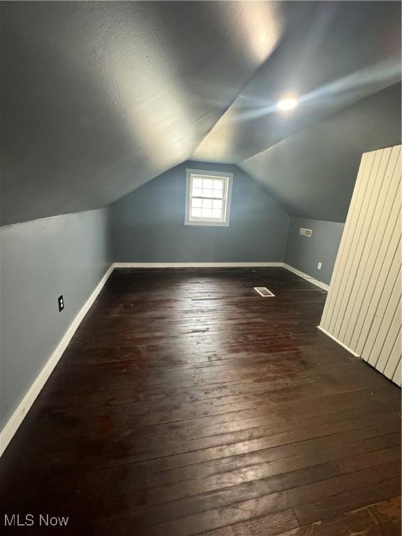 additional living space featuring vaulted ceiling, hardwood / wood-style flooring, and baseboards