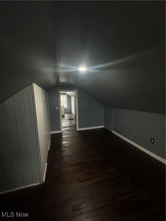 bonus room featuring lofted ceiling, dark wood-type flooring, and baseboards