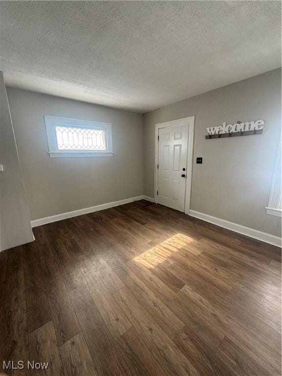 empty room with a textured ceiling, baseboards, and wood finished floors