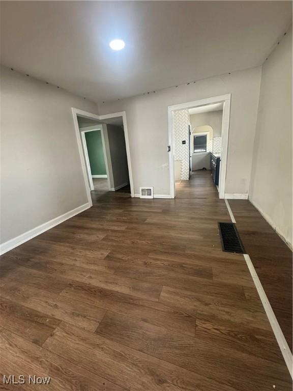 empty room featuring baseboards, visible vents, and dark wood finished floors