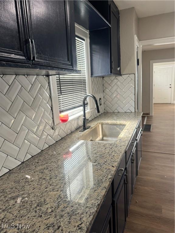 kitchen featuring dark cabinets, a sink, and wood finished floors