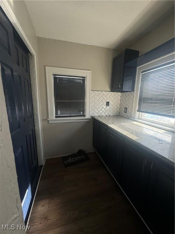 kitchen featuring dark wood-style flooring, light stone countertops, and decorative backsplash