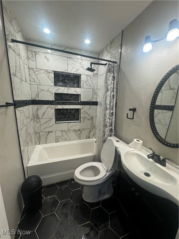 full bathroom featuring a textured wall, tile patterned flooring, toilet, vanity, and shower / bath combination with curtain