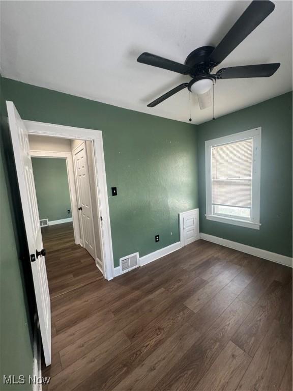 spare room with baseboards, visible vents, and wood finished floors