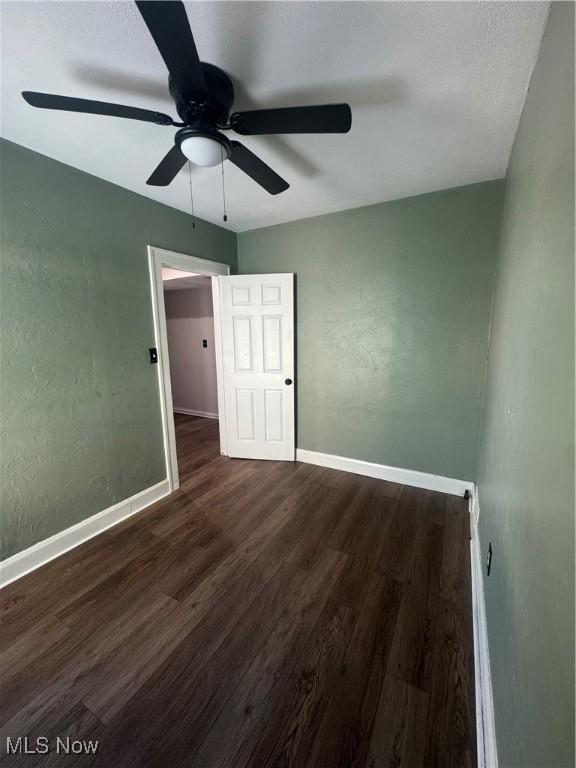 unfurnished bedroom with a ceiling fan, baseboards, wood finished floors, and a textured wall