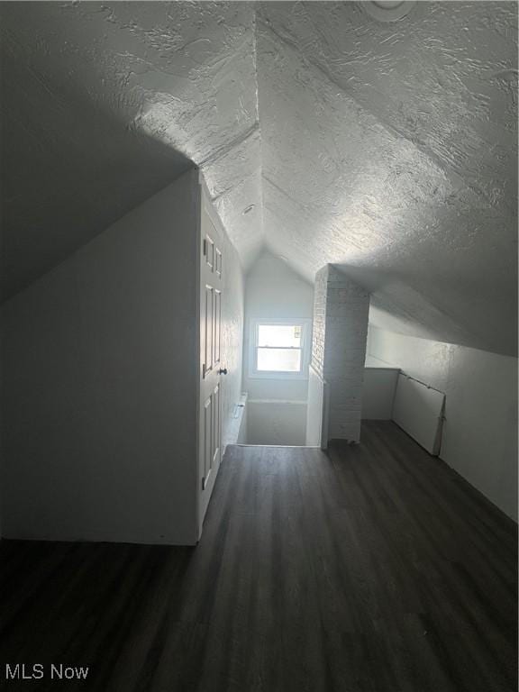 bonus room featuring vaulted ceiling, dark wood finished floors, and a textured ceiling