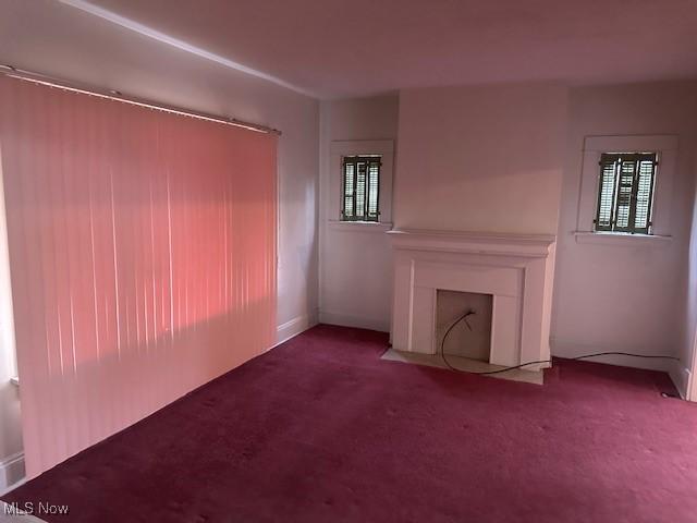 13705 Graham Ave, Cleveland, OH 44112 - unfurnished living room featuring carpet floors, a fireplace with flush hearth, and a wealth of natural light