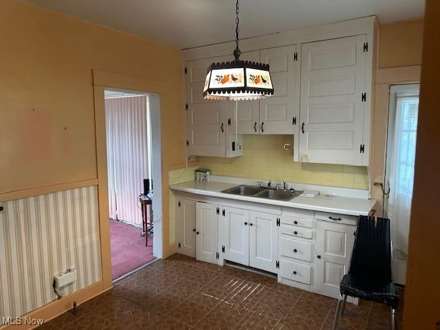 13705 Graham Ave, Cleveland, OH 44112 - kitchen featuring tasteful backsplash, light countertops, white cabinets, and a sink