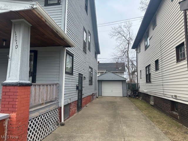 view of property exterior with covered porch, driveway, an outdoor structure, and a garage