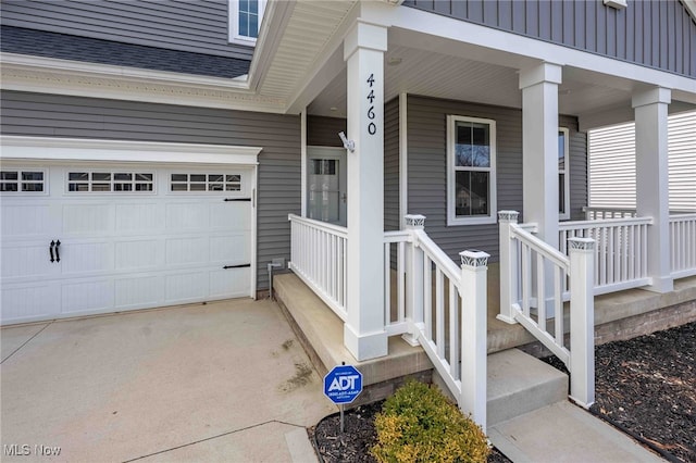 doorway to property with a porch, a shingled roof, board and batten siding, a garage, and driveway