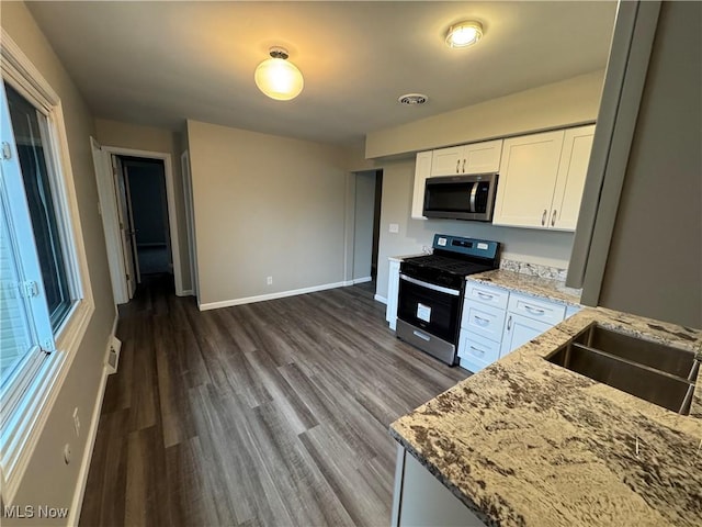 kitchen with baseboards, white cabinets, appliances with stainless steel finishes, light stone counters, and a sink