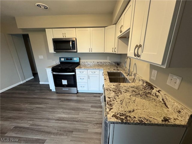 kitchen featuring light stone countertops, visible vents, stainless steel appliances, and a sink