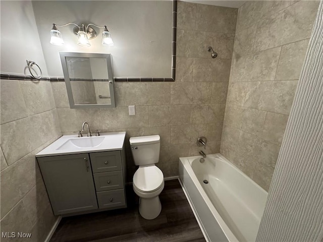 full bathroom with toilet, wood finished floors, vanity, tile walls, and tub / shower combination