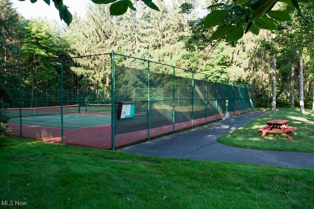 view of tennis court featuring fence and a lawn